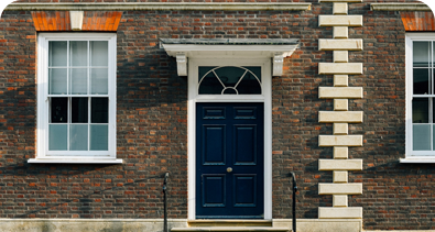 Classic brick house with a navy-blue front door and white-framed windows.